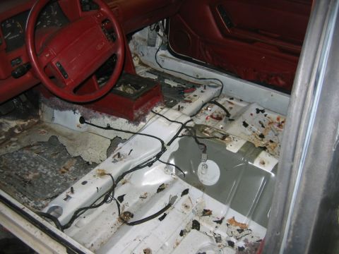 1992 Ford Mustang - The interior of a 1992 Ford Mustang shows significant rust and damage to the floor pans.