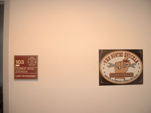 2000 Ford Crown Victoria - A door plaque and a humorous garage sign are mounted on a wall.