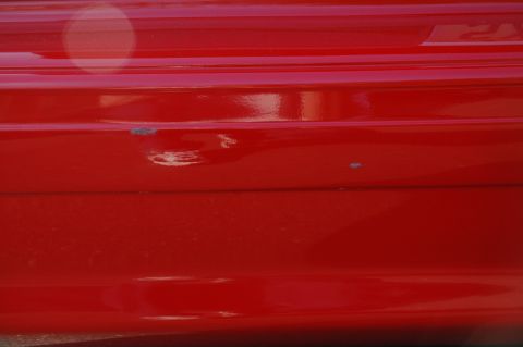 1993 Ford Mustang - This is a close-up view of a red car's bumper, showing some wear and tear.