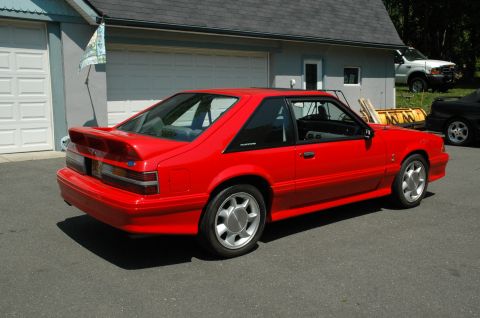1993 Ford Mustang - This red 1993 Ford Mustang coupe features a prominent rear spoiler and unique alloy wheels.