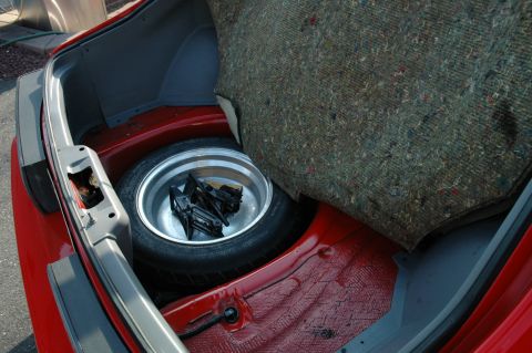1993 Ford Mustang - Spare tire and jack are visible in the trunk of a red car.
