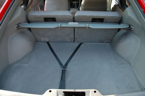 1993 Ford Mustang - The trunk of a car, showing the carpeted floor and the back of the rear seats.