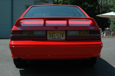 1993 Ford Mustang - Rear view of a red 1993 Ford Mustang, identifiable by its distinctive taillights and body style.