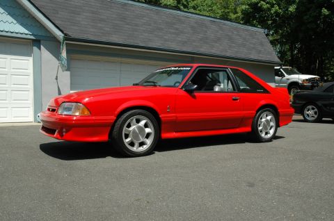 1993 Ford Mustang - A red 1993 Ford Mustang Cobra is parked in a driveway next to a garage.
