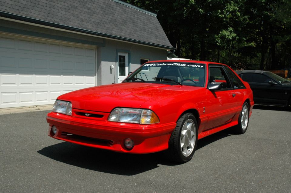 Red 1993 Ford Mustang Cobra coupe parked in driveway, front 3/4 view