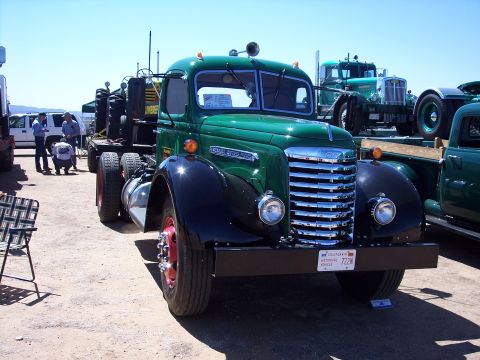 1981 Kenworth W900A - A vintage green truck is parked outdoors, possibly at a show, with other vehicles in the background.