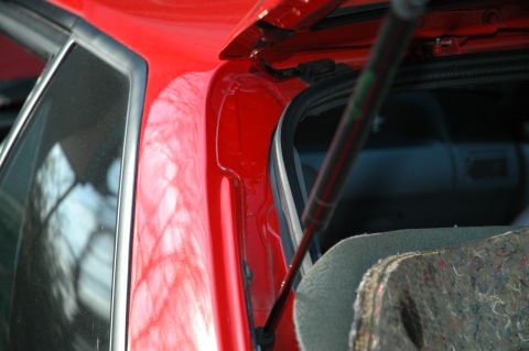 1993 Ford Mustang - The rear trunk area of a 1993 Ford Mustang, showing the red paint and a gas strut.