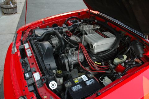 1993 Ford Mustang - The engine bay of a red 1993 Ford Mustang Cobra shows the V8 engine and associated components.