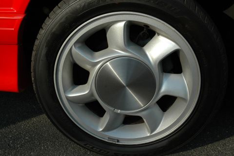 1993 Ford Mustang - Close-up of a silver five-spoke wheel on a red vehicle.