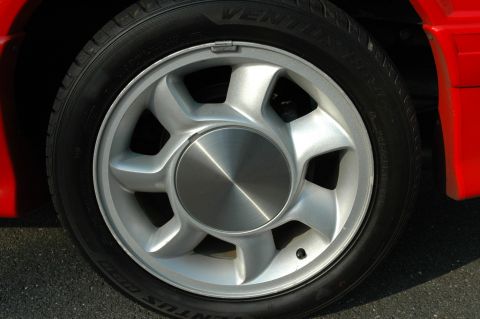 1993 Ford Mustang - Close-up of a wheel and tire on a red vehicle.