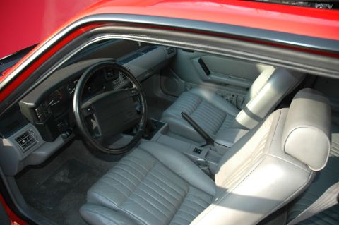 1993 Ford Mustang - The interior of a red 1993 Ford Mustang shows gray leather seats, dashboard, and steering wheel.