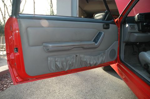 1993 Ford Mustang - Interior view of a red 1993 Ford Mustang Cobra, focusing on the driver's side door panel details.
