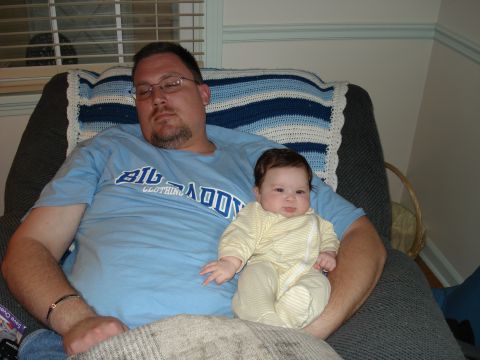 2000 Ford Crown Victoria - A man holds a baby while sitting in a chair, both dressed casually.