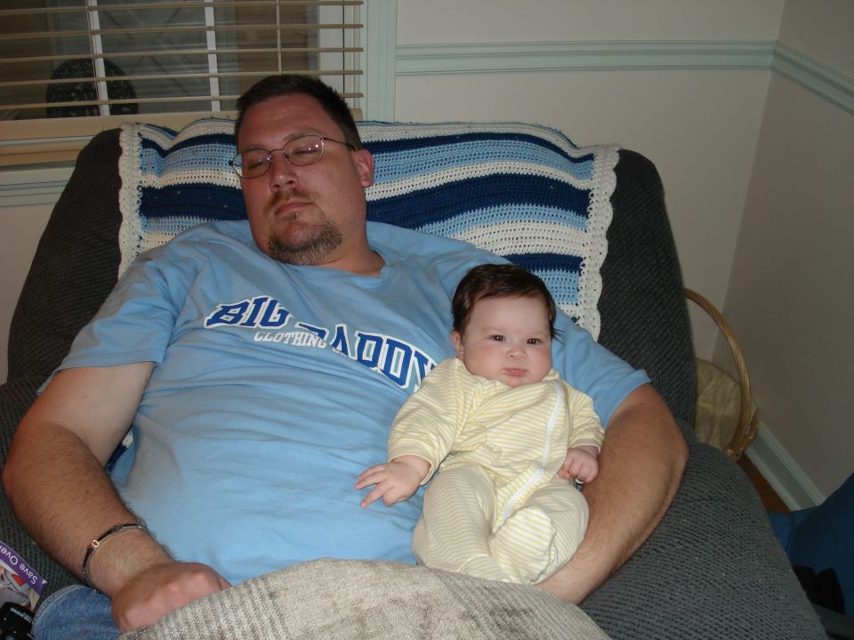 Man holding a baby, both wearing casual clothes