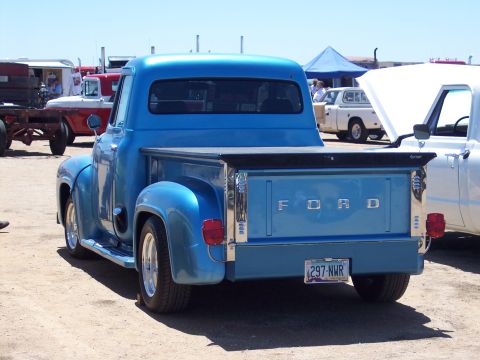 1981 Kenworth W900A - A classic blue 1956 Ford F-series pickup truck is displayed at an outdoor event, with other vehicles visible in the background.