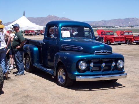 1981 Kenworth W900A - A classic Ford pickup truck is displayed at an outdoor event, with other vehicles and tents visible.
