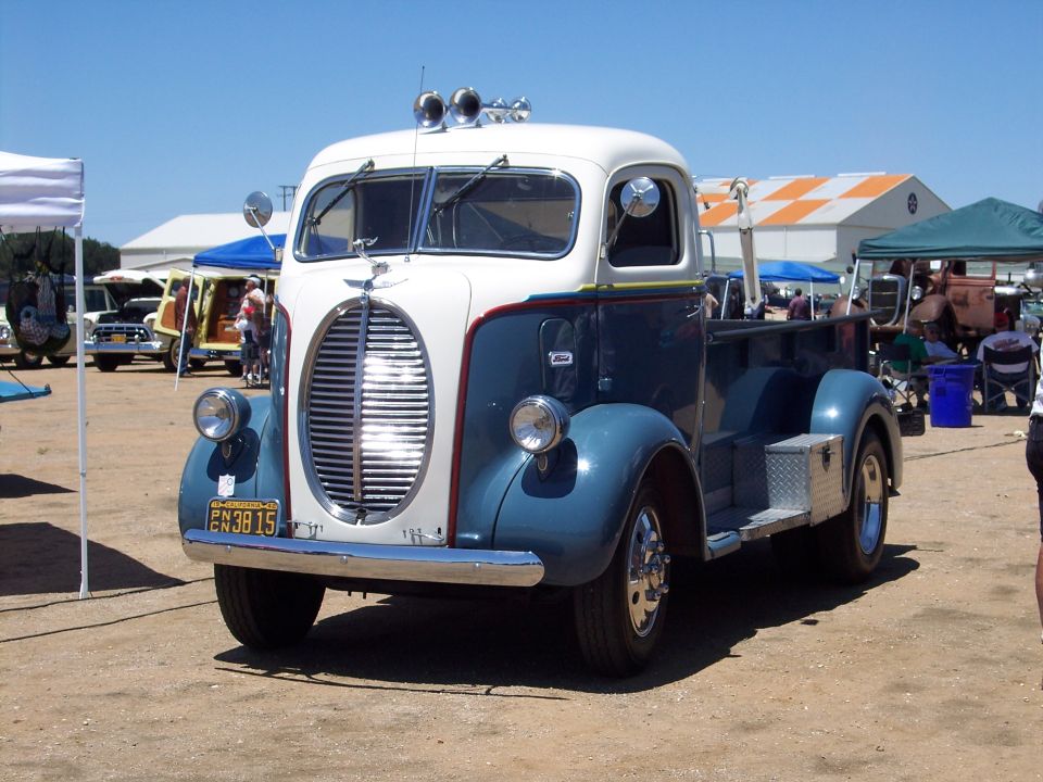 Restored 1930s Ford cab-over truck in blue and cream with oval chrome grille at a car show