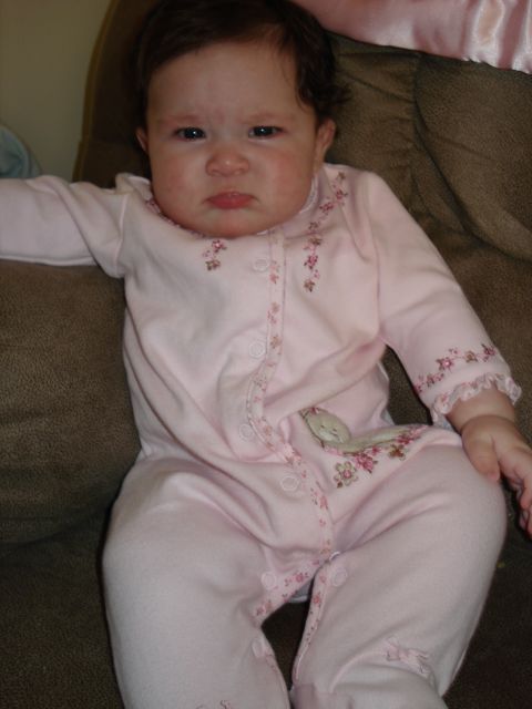 2000 Ford Crown Victoria - A baby wearing pink pajamas with floral accents sits on a couch, looking displeased.