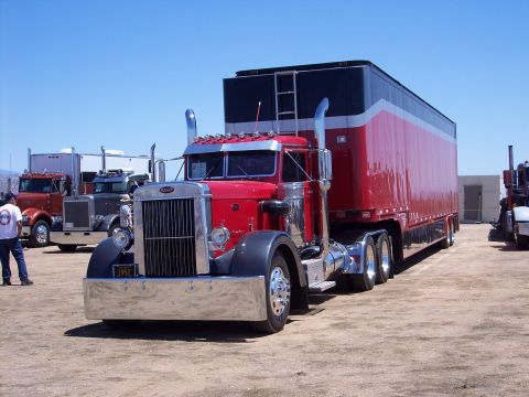 1981 Kenworth W900A - A classic Peterbilt semi-truck is parked outdoors with other trucks in the background under a clear blue sky.