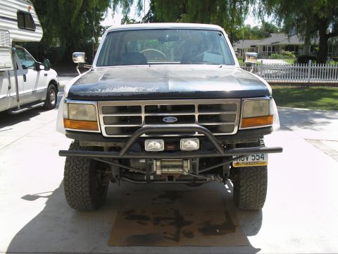 1990 Ford Bronco - This modified Ford F-Series truck features an aftermarket bumper and winch, parked next to an RV.