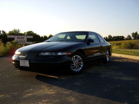 1996 Mercury Grand Marquis - A black 1993 Lincoln Mark VIII is captured in a three-quarter front view, parked beside a road closed sign.
