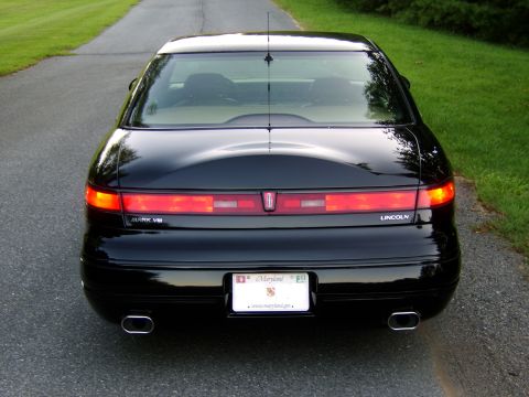 1996 Mercury Grand Marquis - Rear view of a black Lincoln Mark VIII parked on a paved road with grassy shoulders.