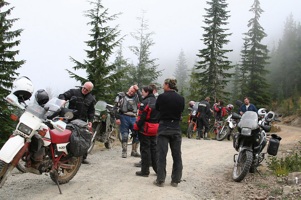 Group of people with motorcycles on a dirt road in a forest