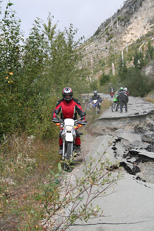 1979 Ford Bronco - A group of motorcyclists ride on a treacherous mountain road damaged by landslides and debris.