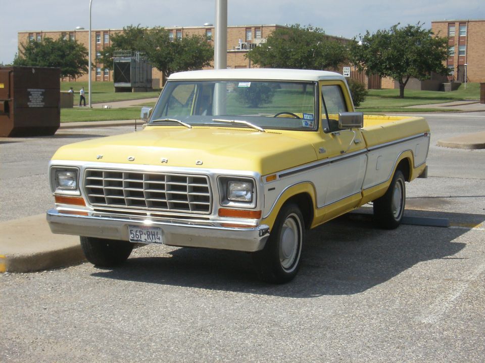 Front three-quarter view of yellow and white classic Ford pickup in a lot