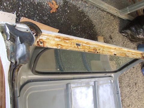 1979 Ford Bronco - The heavily rusted door frame of a vehicle is shown, revealing its internal structure and window seal.