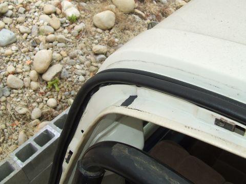 1979 Ford Bronco - Close-up view of the door frame and seal on a white vehicle, showing some wear and tear.