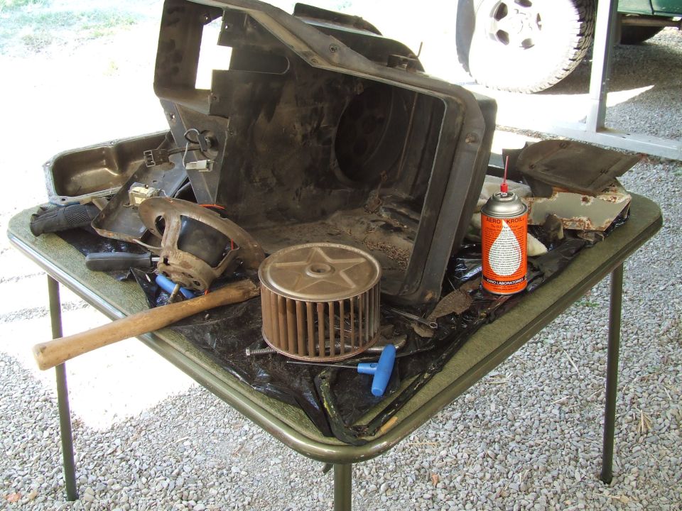 Disassembled HVAC unit and parts on a table, with a can of spray lubricant
