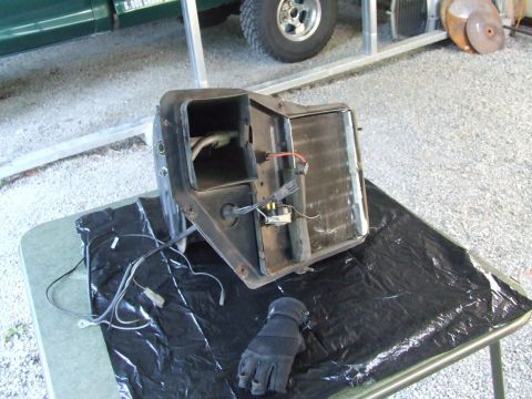 1979 Ford Bronco - Disassembled heater core assembly with associated wiring and a glove resting on a black plastic sheet.