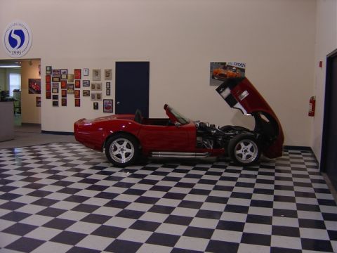 1996 Ford Bronco - A red convertible with its hood open, revealing the engine, sits on a black and white checkered floor.