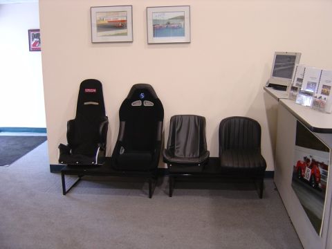 1996 Ford Bronco - A waiting area with racing seats and framed pictures of race cars on the wall.