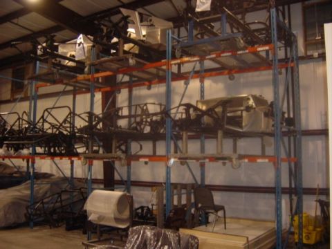 1996 Ford Bronco - Multiple vehicle chassis and components are organized on tall storage racks within a warehouse facility.
