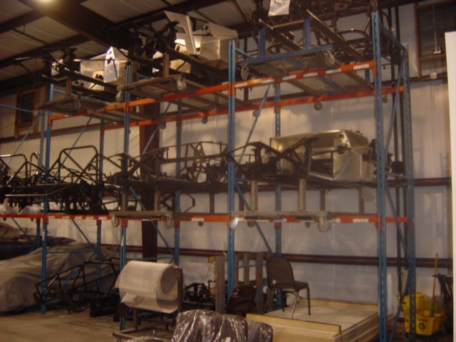 Vehicle chassis and parts stored on industrial racks inside a warehouse