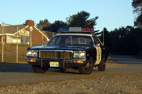 1973 Dodge 1500 - This 1973 Dodge 1500 police car is seen from the front, with a building in the background.