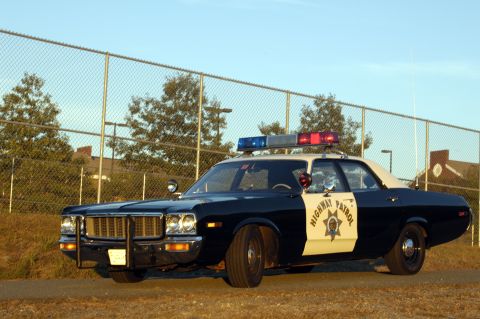1973 Dodge 1500 - A 1974 police car with "HIGHWAY PATROL" markings is parked outdoors near a chain-link fence.