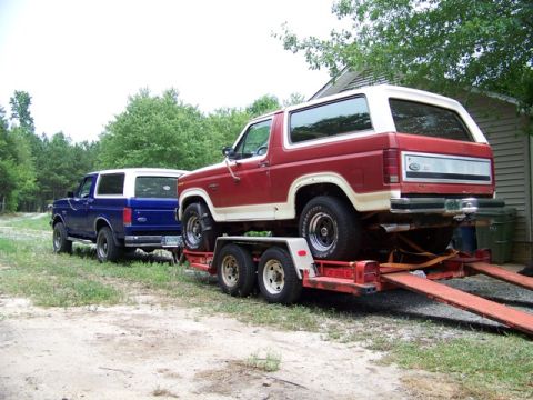1990 Ford Bronco - Two Ford Broncos are visible, one loaded onto a trailer and another parked nearby.