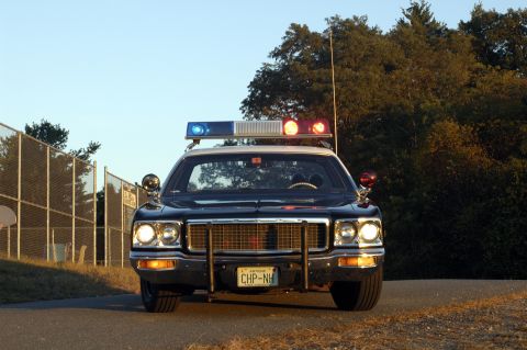 1973 Dodge 1500 - This 1973 police car features a prominent push bumper and a classic light bar, seen from a direct front-facing perspective.