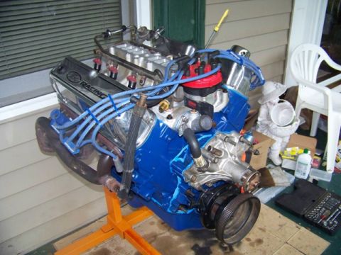 1990 Ford Bronco - A blue V8 engine with chrome valve covers is displayed on an orange stand.