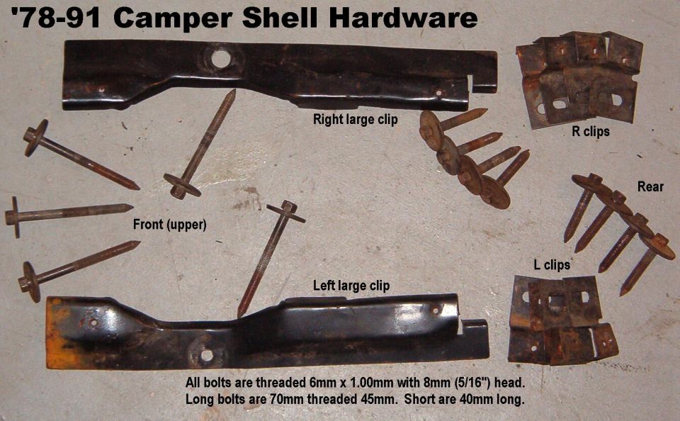 Rusty camper shell mounting hardware: brackets, clips, and bolts laid out on a surface
