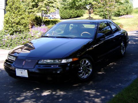 1996 Mercury Grand Marquis - A black 1996 Mercury Grand Marquis with chrome wheels is parked outside on a sunny day.