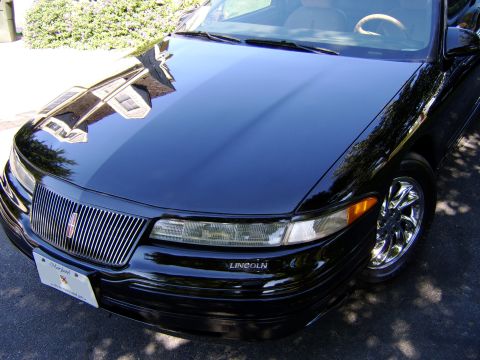 1996 Mercury Grand Marquis - Black Lincoln Town Car, front view, showing chrome grille and bumper detail.