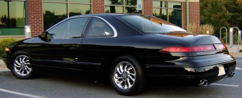 1996 Mercury Grand Marquis - A black coupe with chrome wheels is parked in front of a brick building.