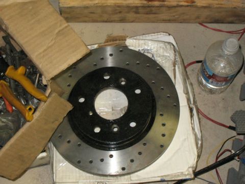 2001 Pontiac Trans Am - A perforated brake rotor is shown in its packaging, alongside tools and a bottle of water.