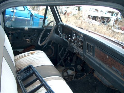 1979 Ford Bronco - Interior view of a weathered vehicle in a junkyard, with other vehicles visible in the background.