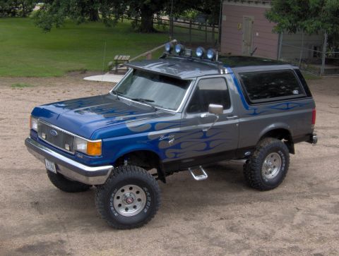 1987 Ford Bronco - This lifted 1987 Ford Bronco features a two-tone paint scheme with flame graphics and auxiliary lighting.
