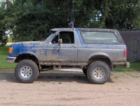 1987 Ford Bronco - This lifted 1987 Ford Bronco is covered in mud, showing off its off-road capabilities.